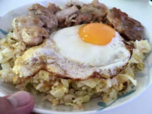 チャーハン、目玉焼き、肉を皿に盛り付けた