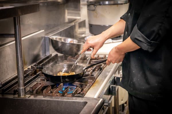 鉄フライパンで調理中の料理人